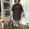 Hazel and her dog milo stand in front of four textile artworks depicting stitched landscapes and an underwater scene with a mermaid.